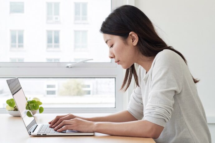 デスクワークで背中が丸まり肩が内に入った姿勢の女性
